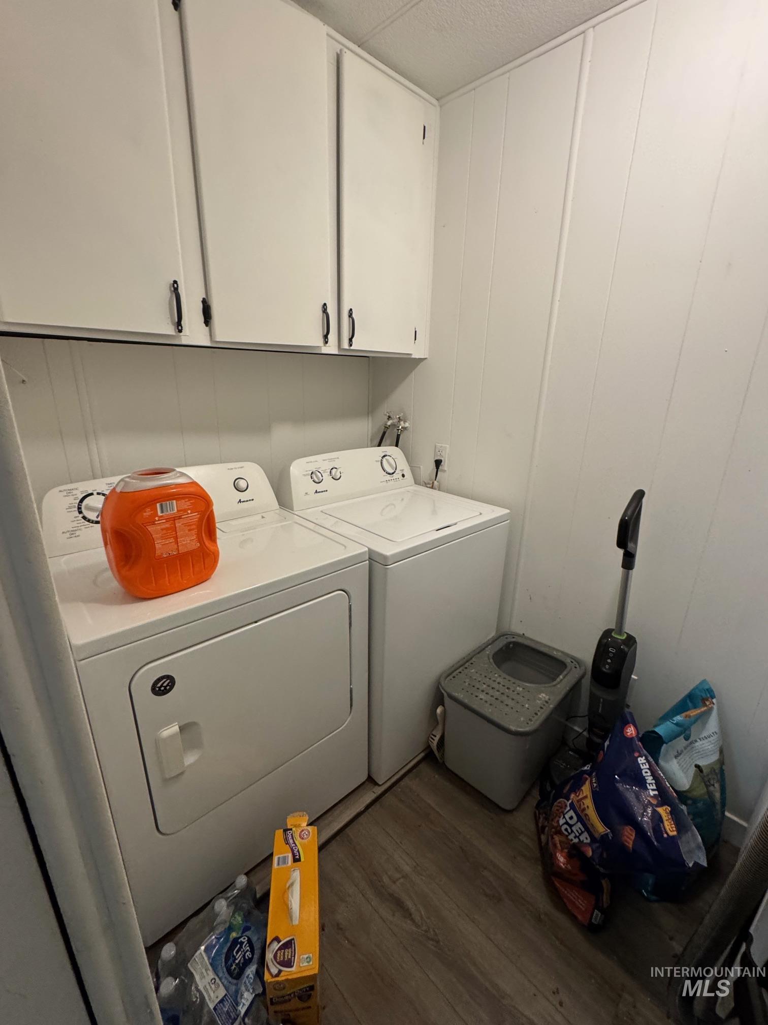 Laundry room with cabinet space, wood finished floors, and washing machine and clothes dryer