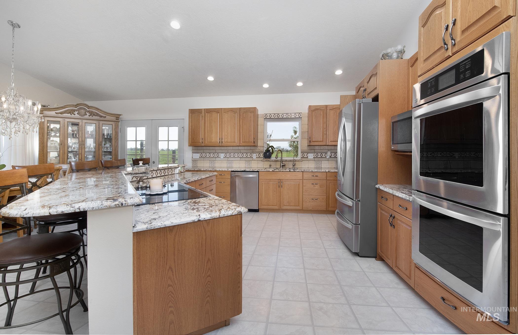 Kitchen with stainless steel appliances, a breakfast bar area, healthy amount of natural light, light stone counters, and recessed lighting