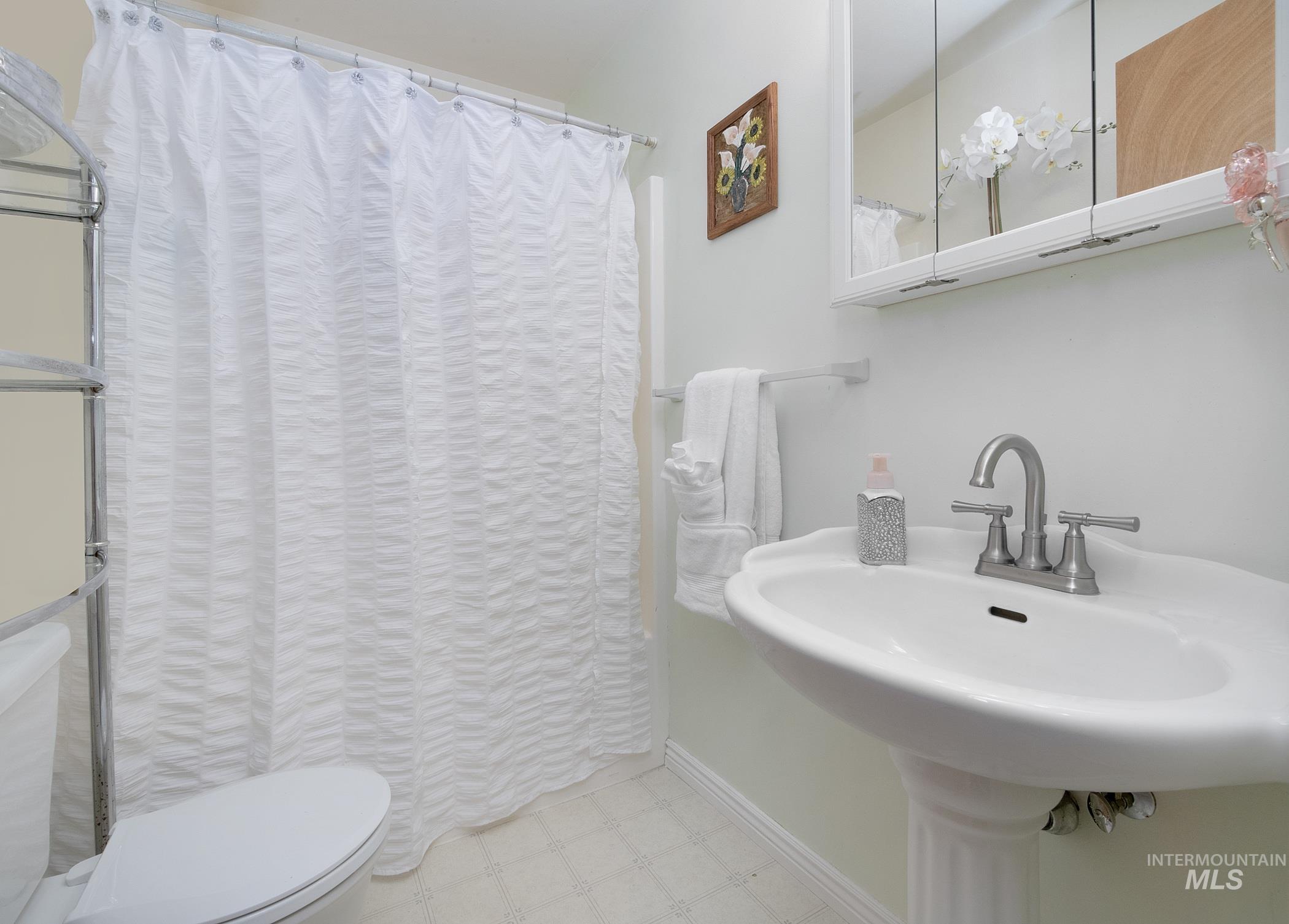 Bathroom with tile patterned floors and a shower with shower curtain