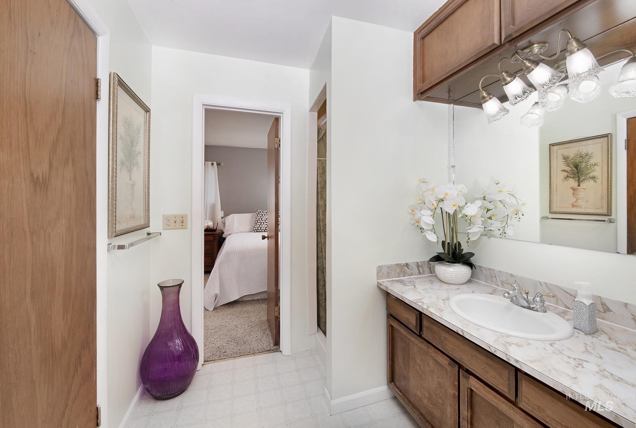 Ensuite bathroom featuring tile patterned floors, vanity, and a shower
