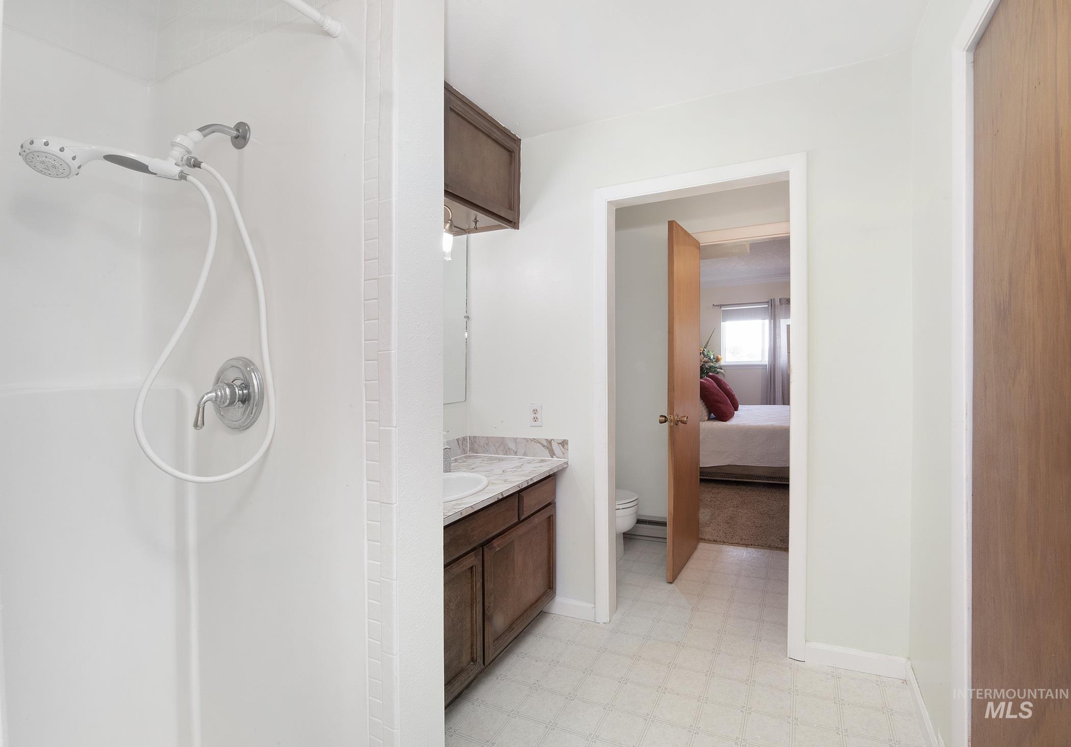 Ensuite bathroom with tile patterned floors, vanity, and a shower