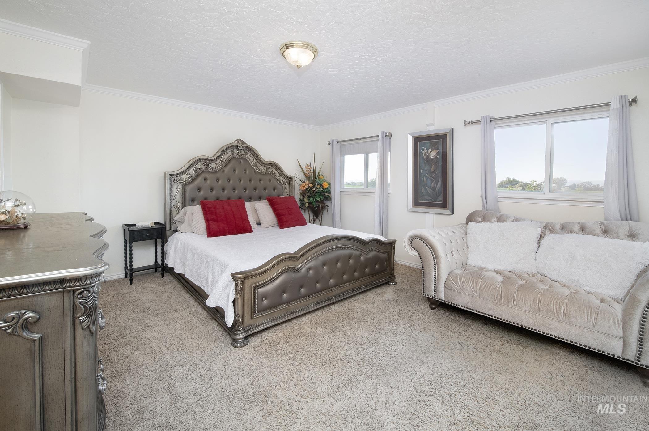 Carpeted bedroom featuring ornamental molding and a textured ceiling