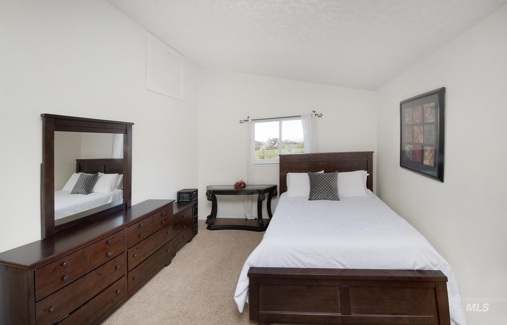 Bedroom with lofted ceiling and light carpet