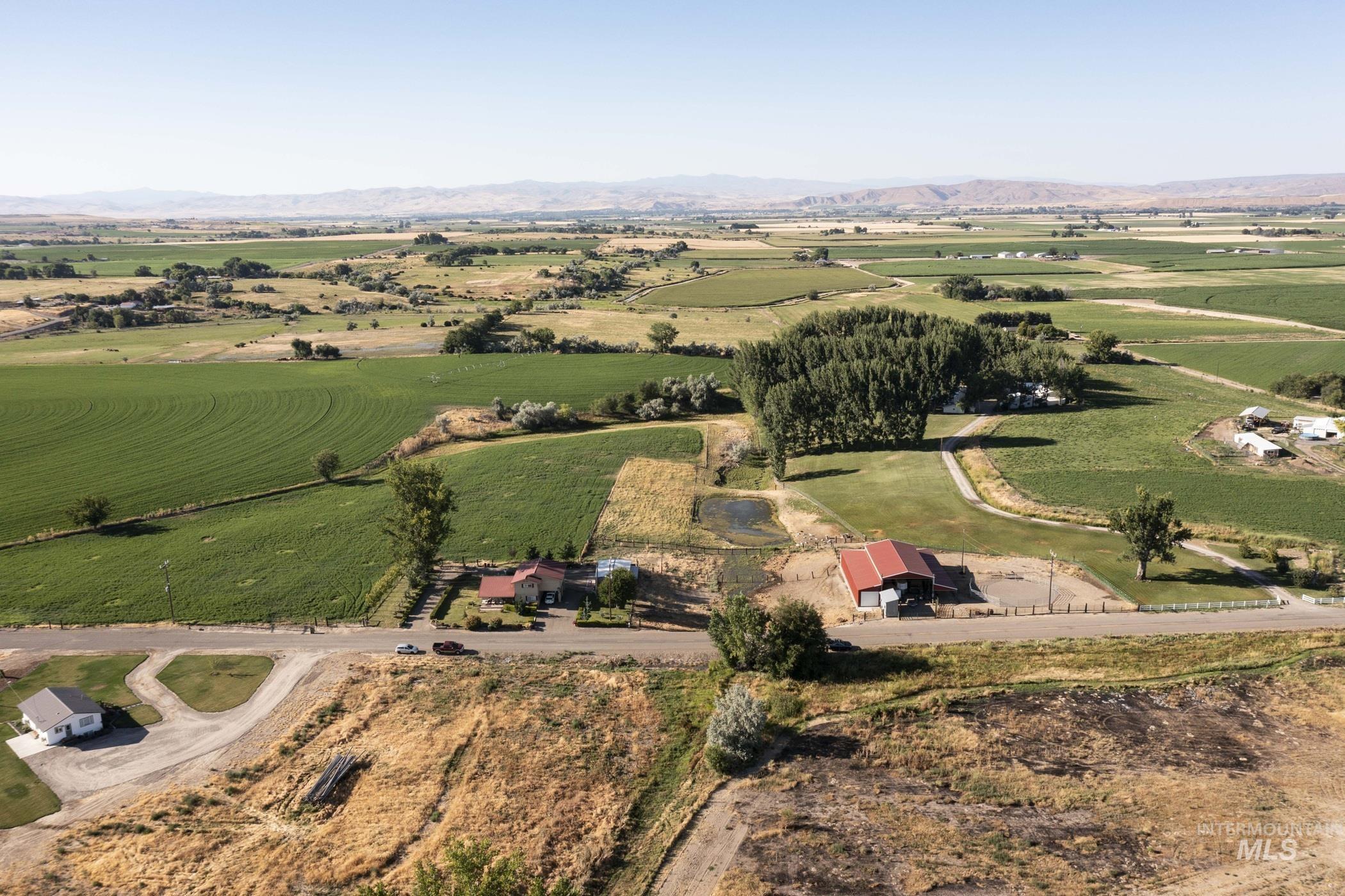Aerial view of property and surrounding area featuring rural landscape and a mountain backdrop