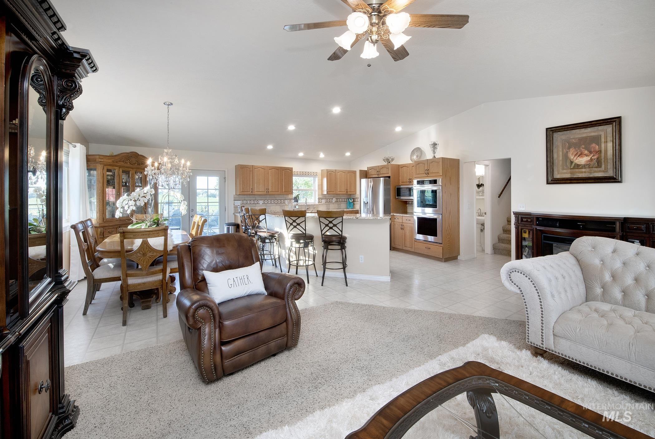 Living room with light tile patterned flooring, ceiling fan, recessed lighting, lofted ceiling, and a chandelier