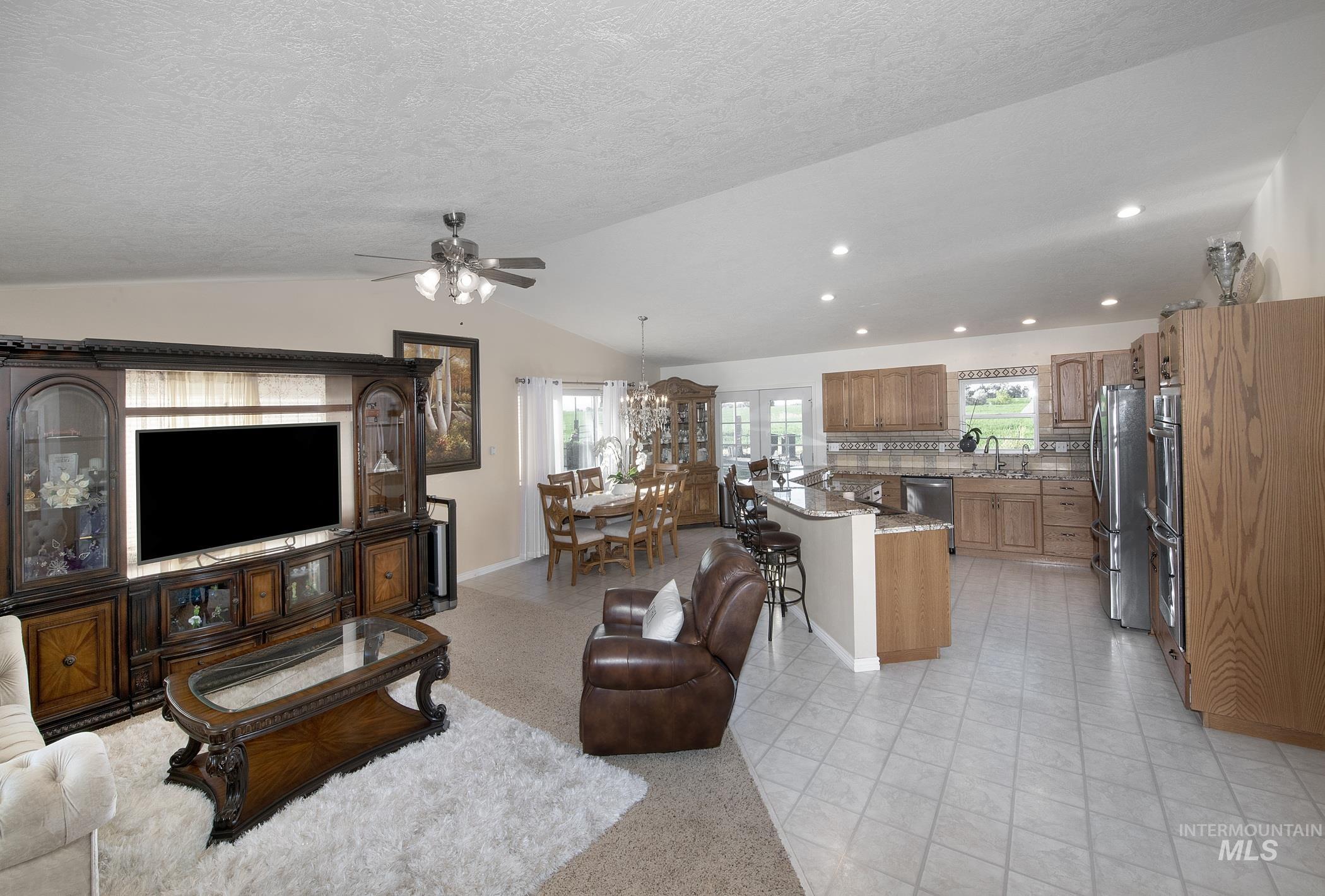 Living room featuring vaulted ceiling, a ceiling fan, recessed lighting, a textured ceiling, and light tile patterned floors