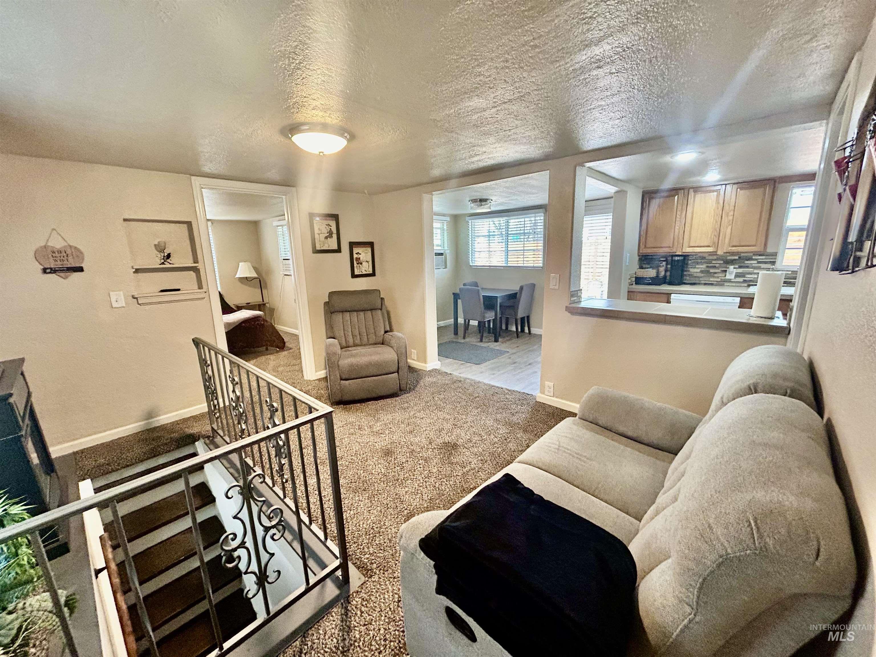 Carpeted living room featuring baseboards and a textured ceiling