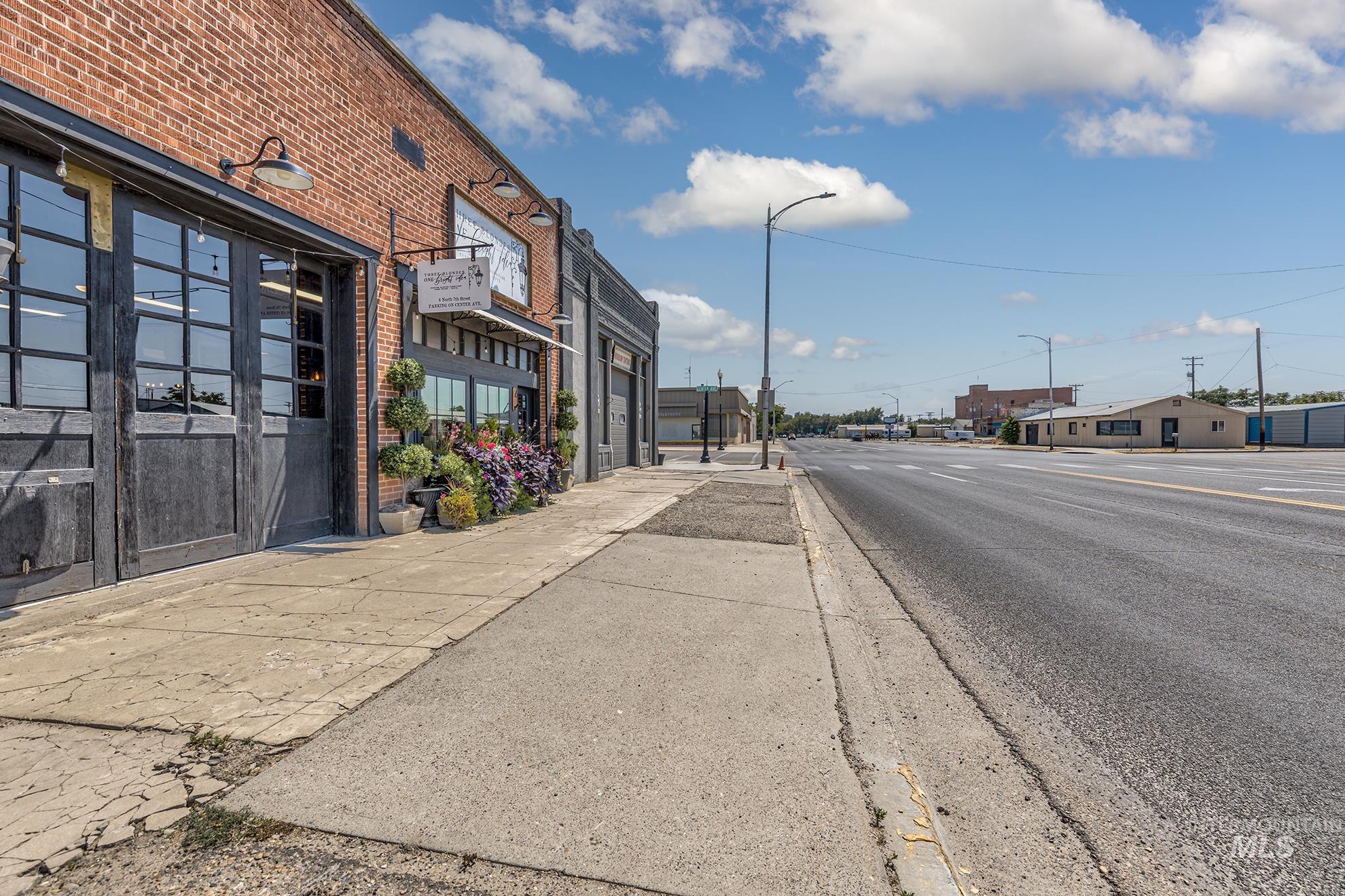 View of asphalt street featuring street lighting, sidewalks, and curbs