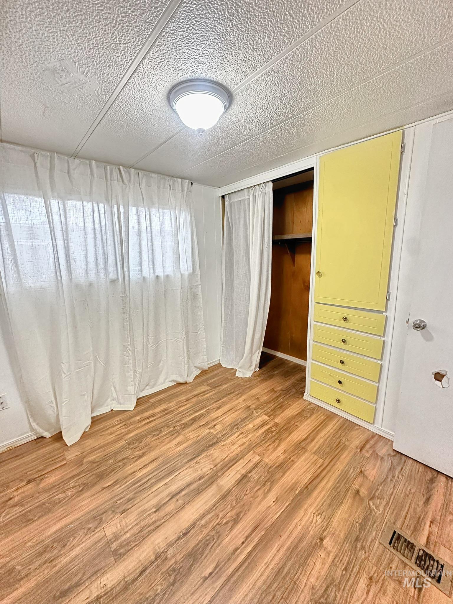 Unfurnished bedroom featuring light wood-style floors, a textured ceiling, and a closet