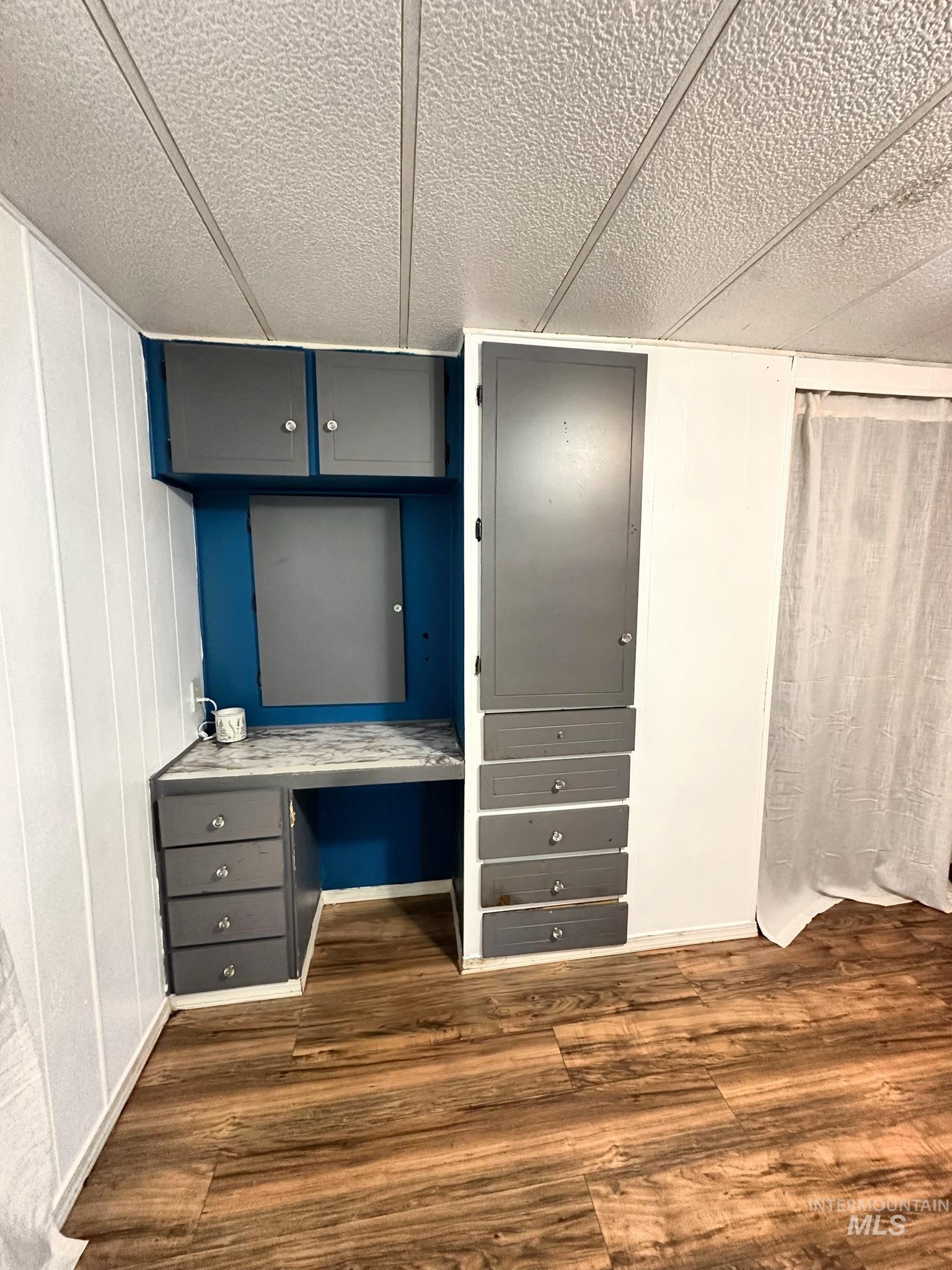 Unfurnished bedroom with built in study area, dark wood-style flooring, and a textured ceiling