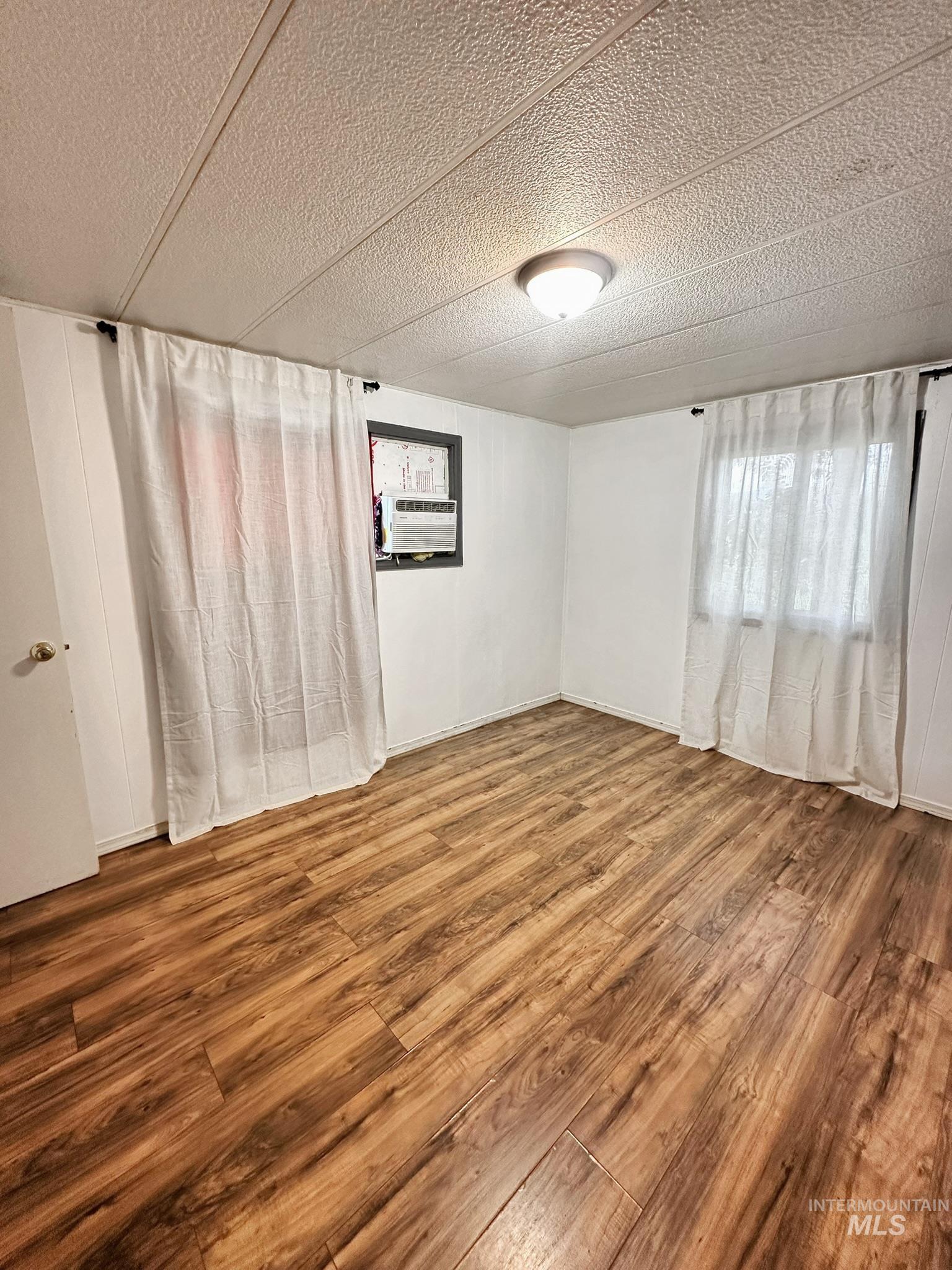 Unfurnished room with a textured ceiling and wood finished floors