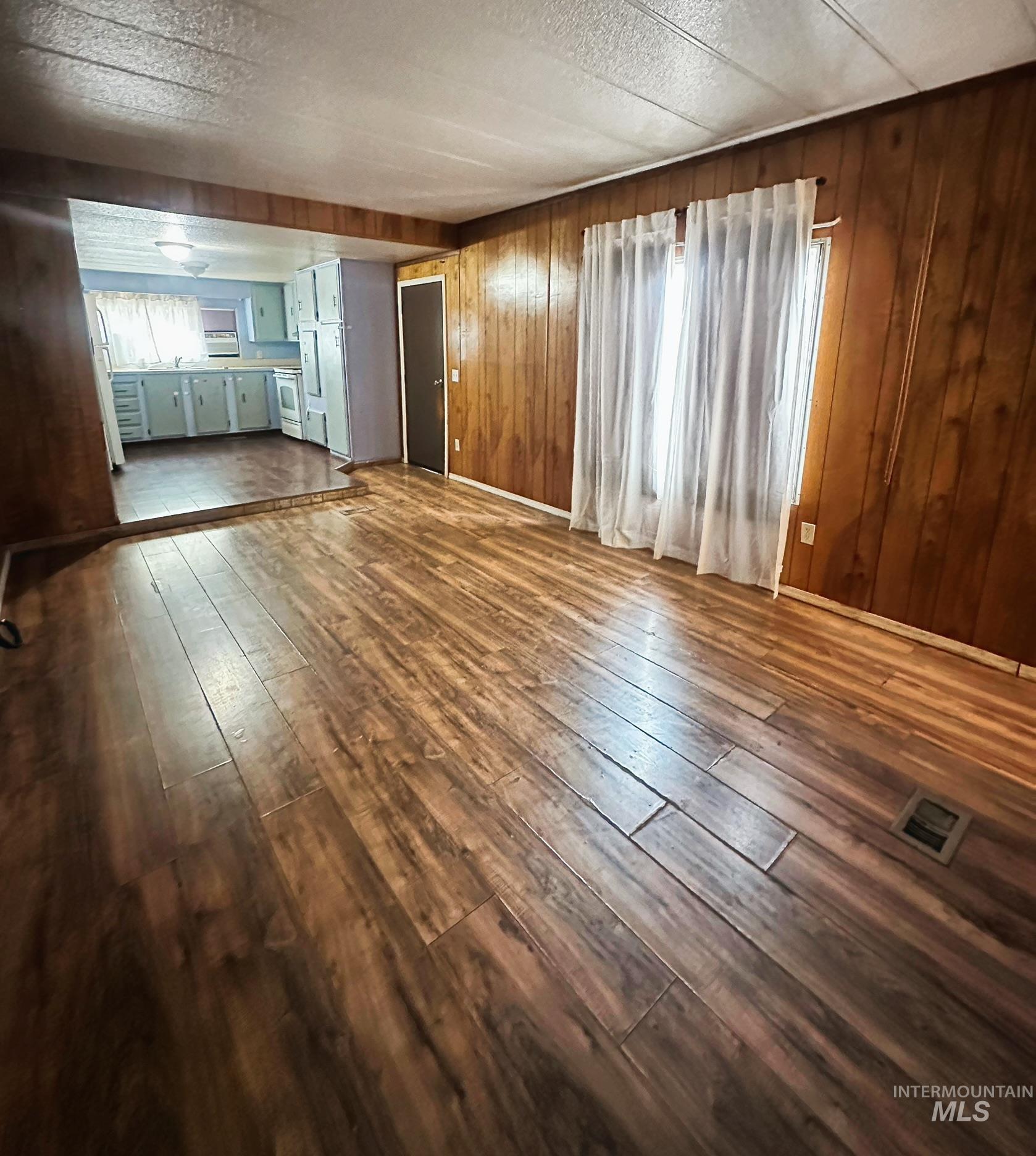 Unfurnished living room with dark wood-type flooring and wooden walls