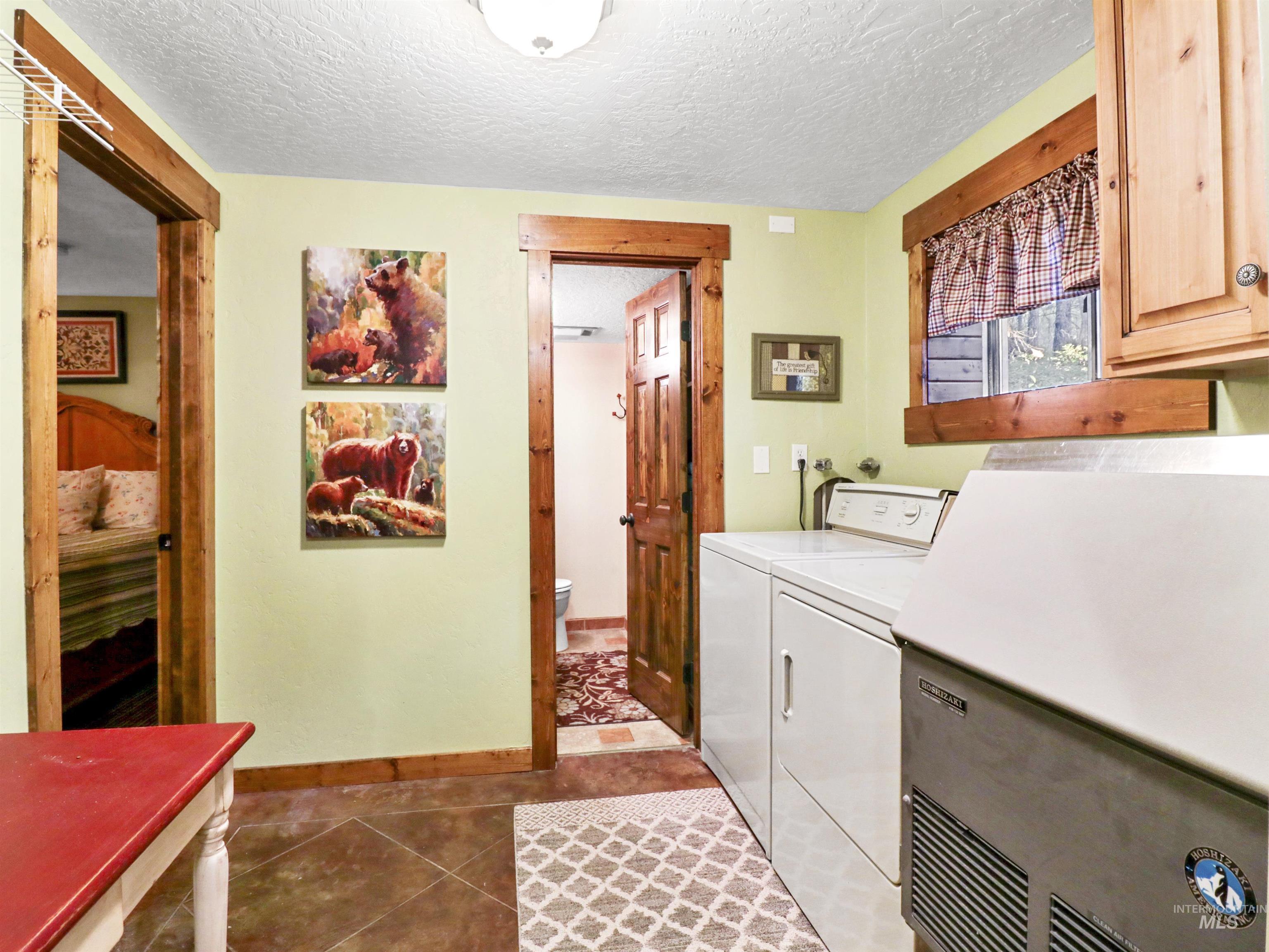 Laundry room featuring cabinet space, separate washer and dryer, a textured ceiling, and light tile patterned floors