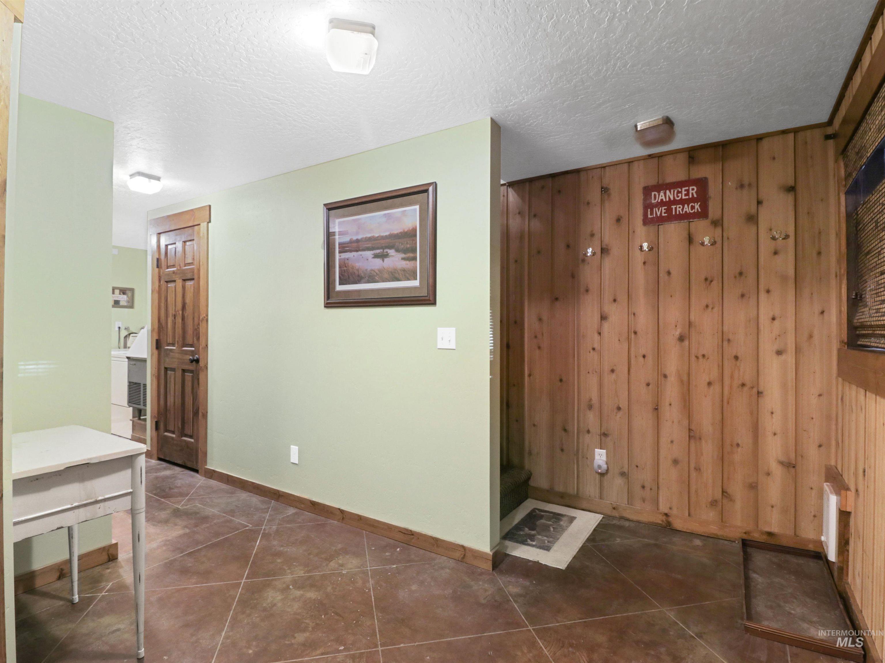 Hall with wood walls, a textured ceiling, and dark tile patterned flooring