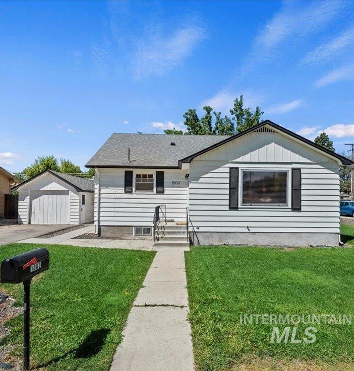 Bungalow-style home with an outdoor structure, a front lawn, driveway, and a garage
