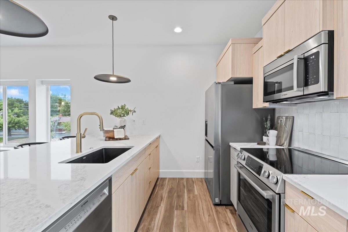 Kitchen with light cabinets, stainless steel appliances, dark floors, quartz counters, and recessed lighting.