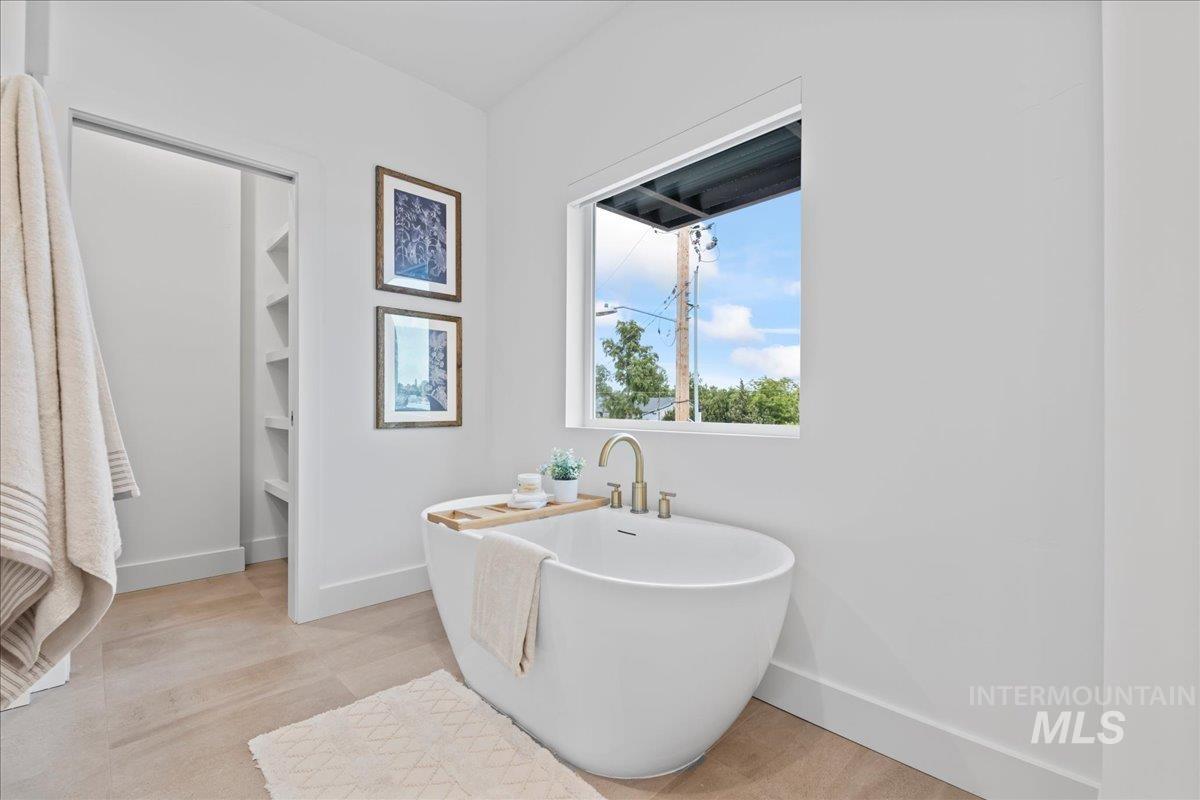 Full bath featuring a freestanding tub and baseboards
