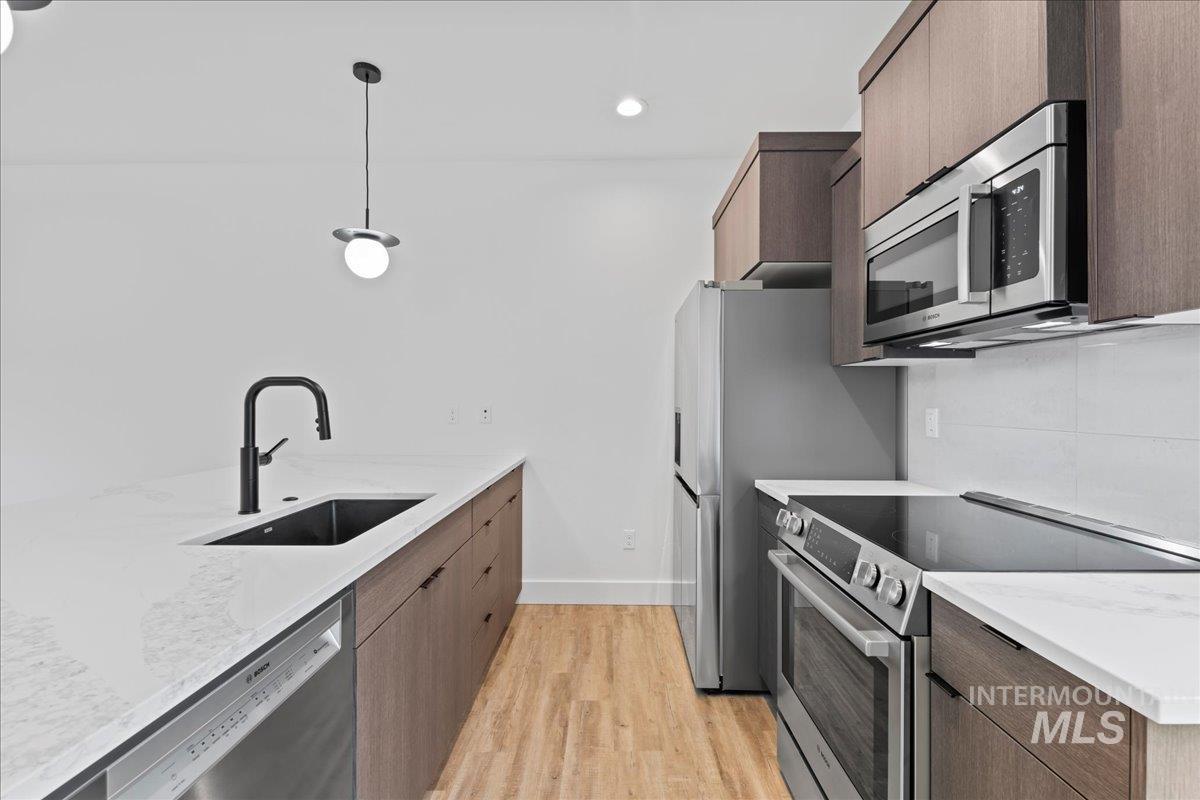 Shown unit 108 w/dark cabinet option, SS appliances, Bosch DW, and oven, light LVP floors, pendant lighting, and quartz counters.