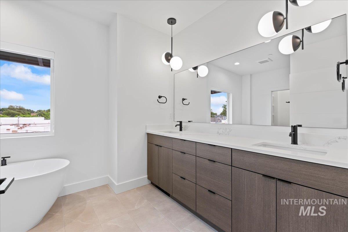 Bathroom with double vanity, a soaking tub, and tile patterned floors