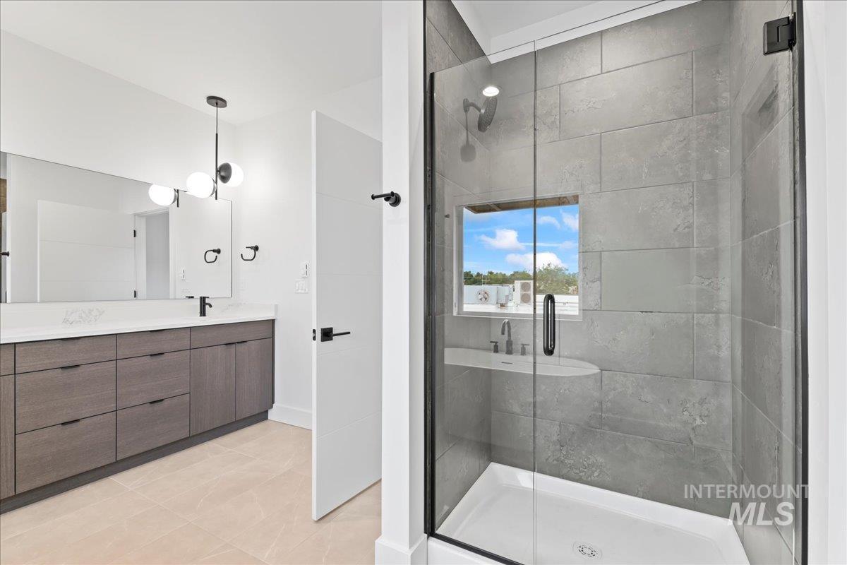 Full bathroom with vanity, a shower stall, and light tile patterned flooring