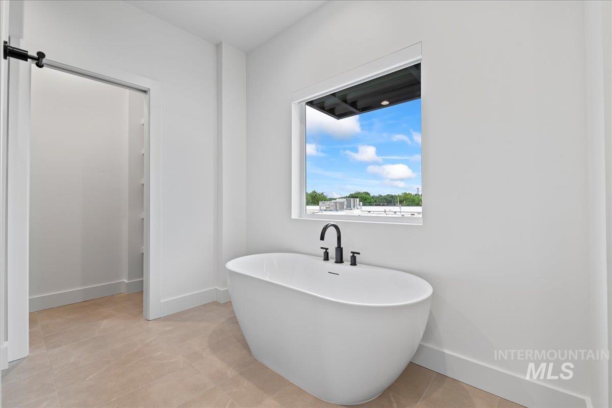 Full bath with a freestanding tub and light tile patterned floors
