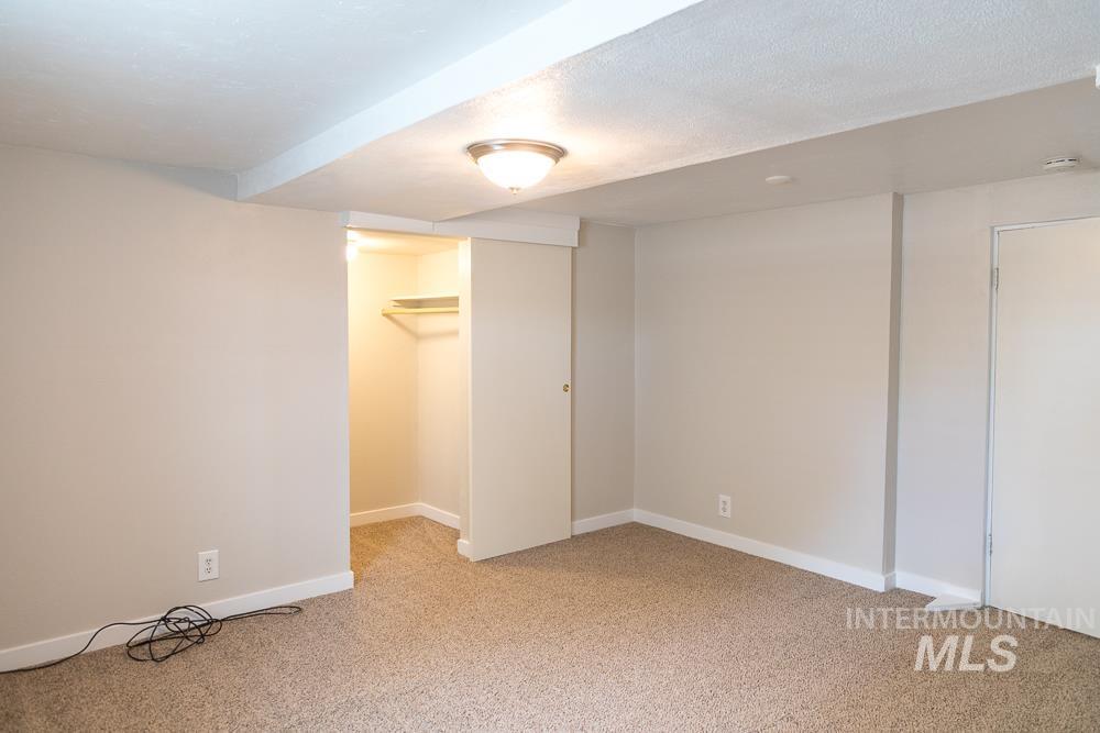Unfurnished bedroom featuring light colored carpet, a textured ceiling, and a walk in closet
