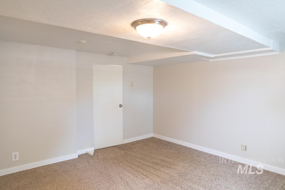 Empty room featuring light colored carpet and a textured ceiling