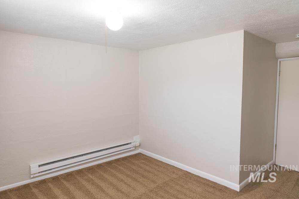 Unfurnished room featuring carpet floors, a baseboard heating unit, and a textured ceiling