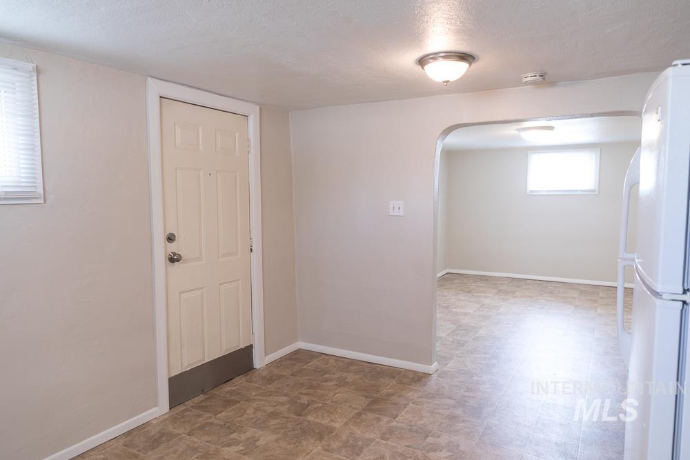 Below grade area with a textured ceiling, freestanding refrigerator, and arched walkways