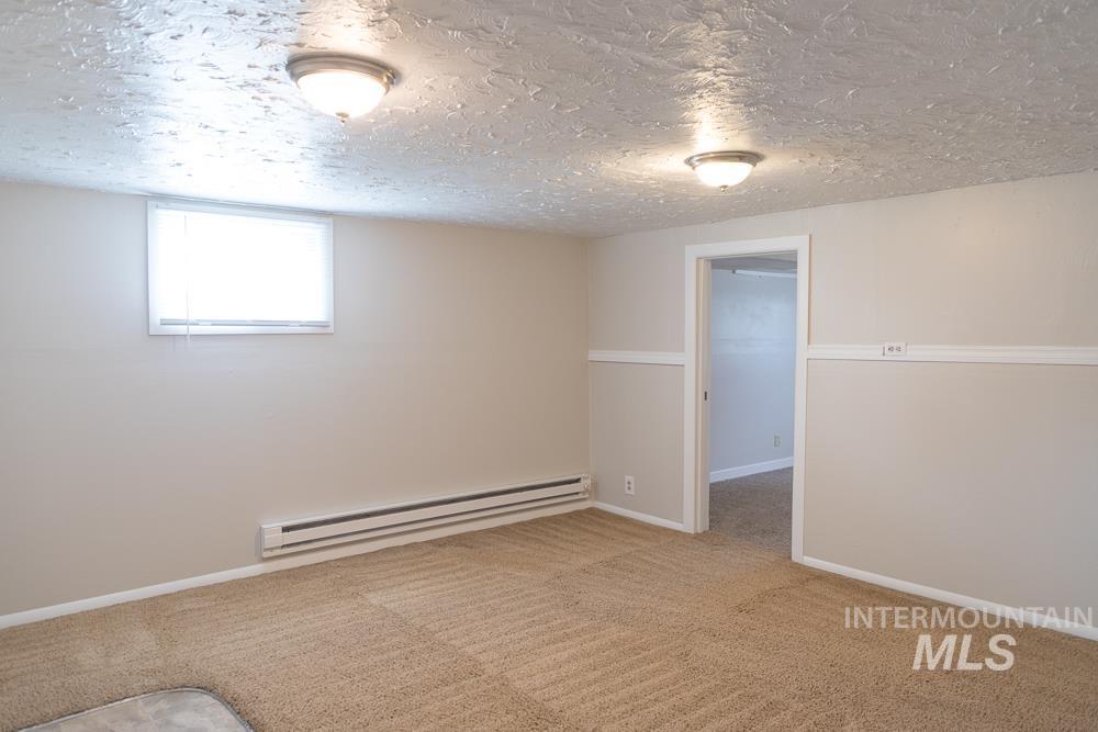 Basement with a baseboard radiator, carpet, and a textured ceiling