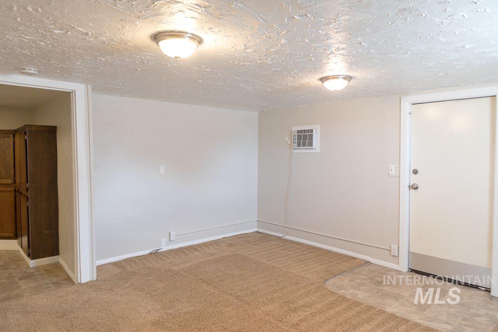 Empty room with a textured ceiling and light carpet