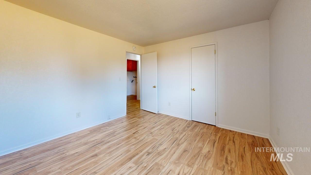 Unfurnished bedroom with light wood-style floors and baseboards