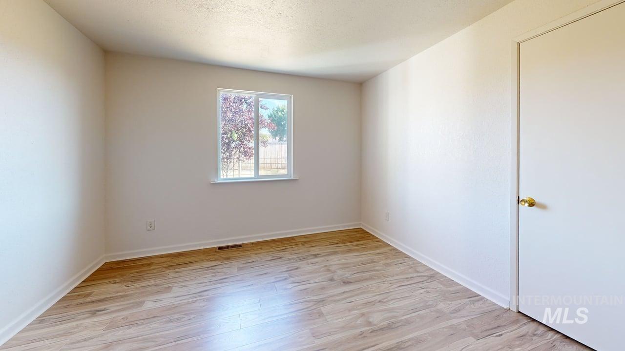 Empty room featuring light wood-type flooring and a textured ceiling