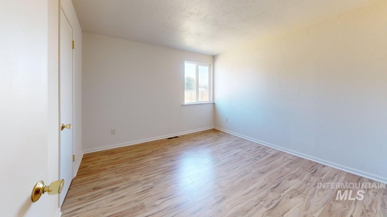 Unfurnished room featuring light wood-style flooring and a textured ceiling