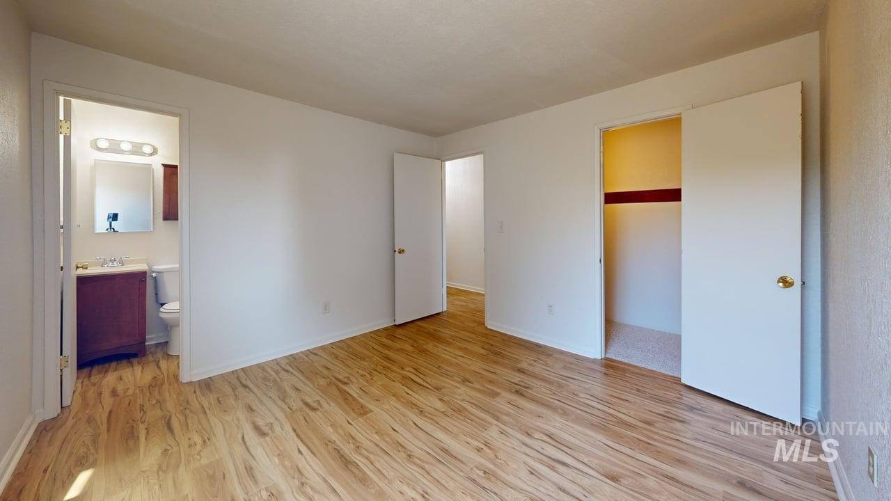 Unfurnished bedroom featuring light wood-type flooring and ensuite bath