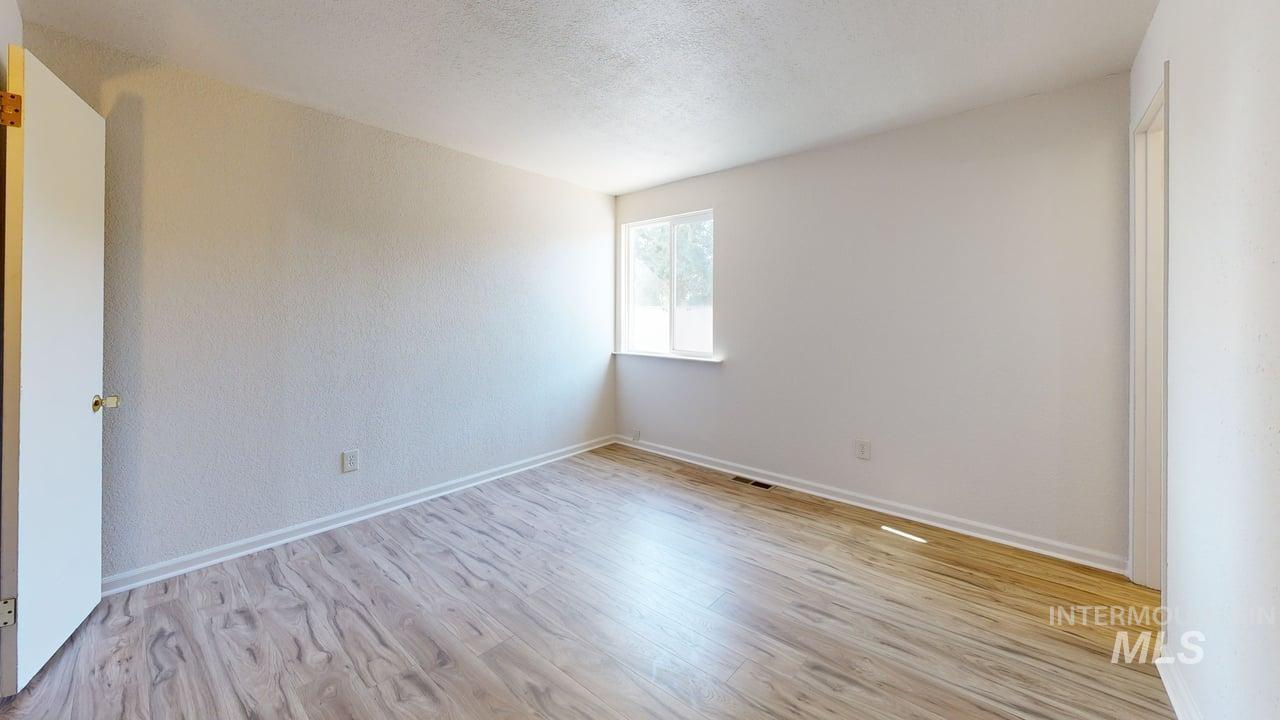 Empty room featuring light wood-style flooring and a textured ceiling