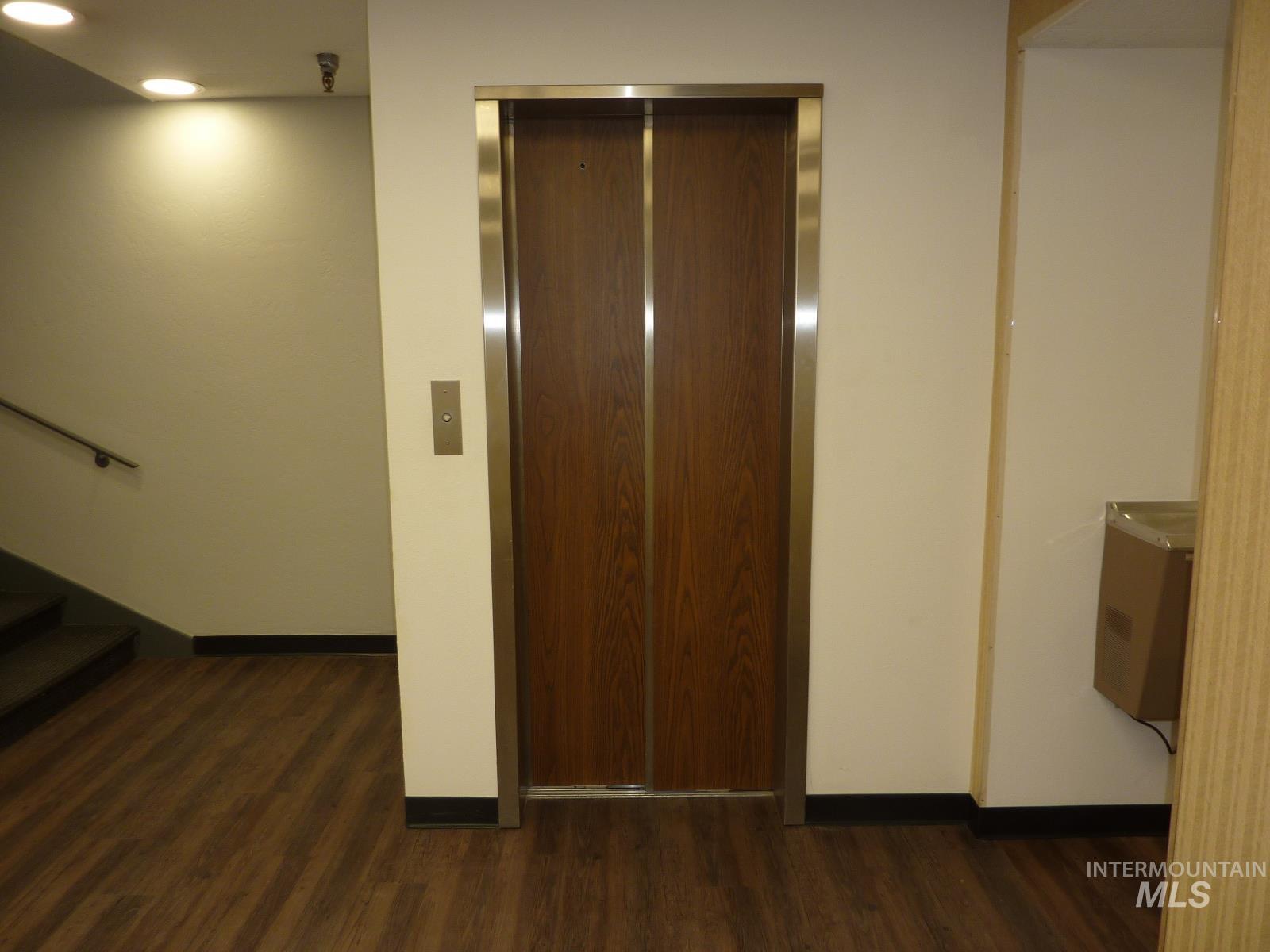 Corridor with elevator, dark wood-style floors, stairway, and recessed lighting