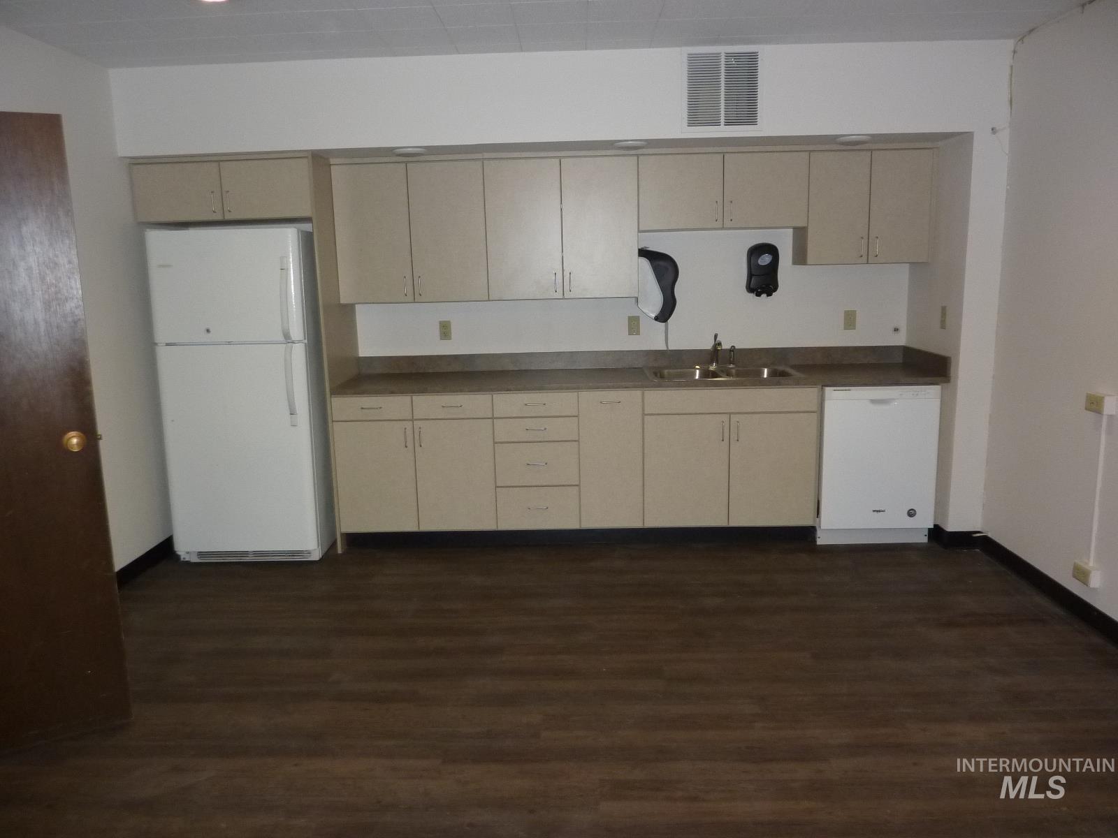 Kitchen with white appliances, cream cabinets, and dark countertops
