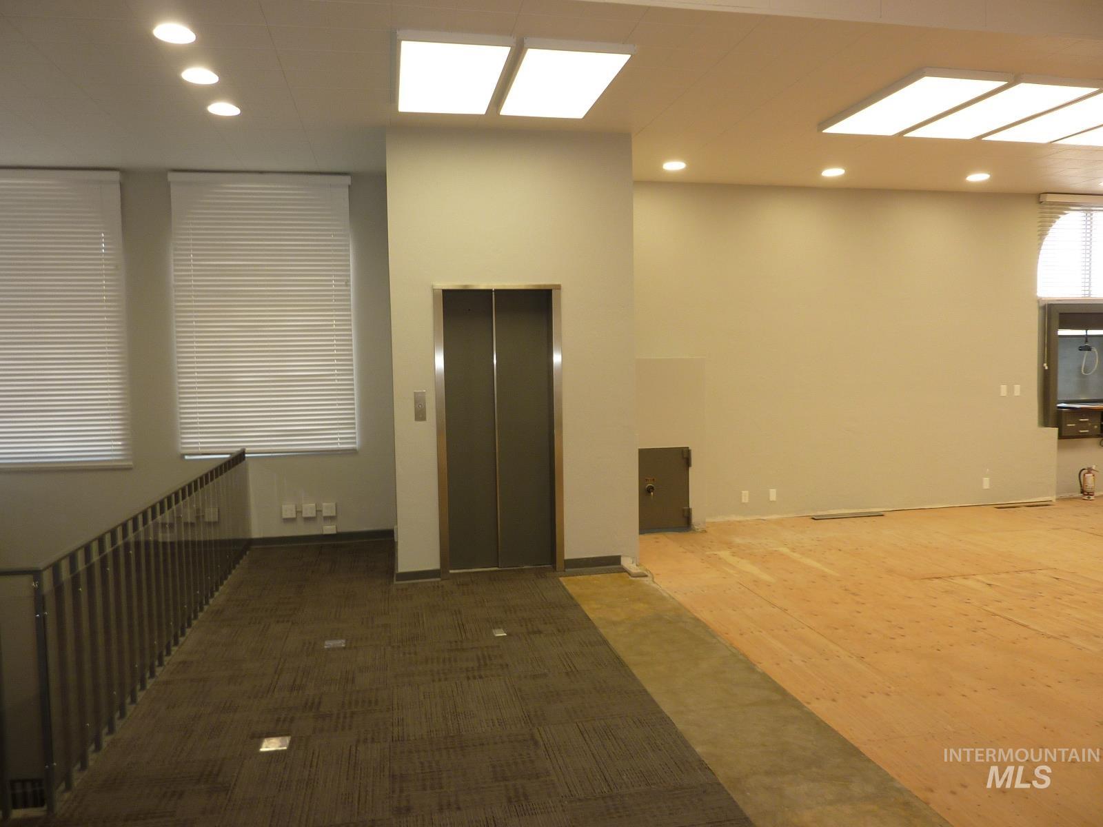 Carpeted empty room featuring elevator and recessed lighting