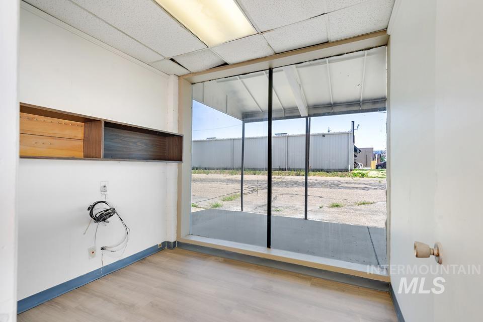 Empty room with a drop ceiling and wood finished floors