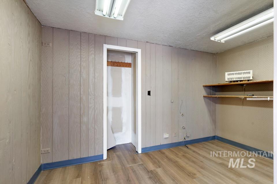 Unfurnished room featuring wood walls, a textured ceiling, and wood finished floors