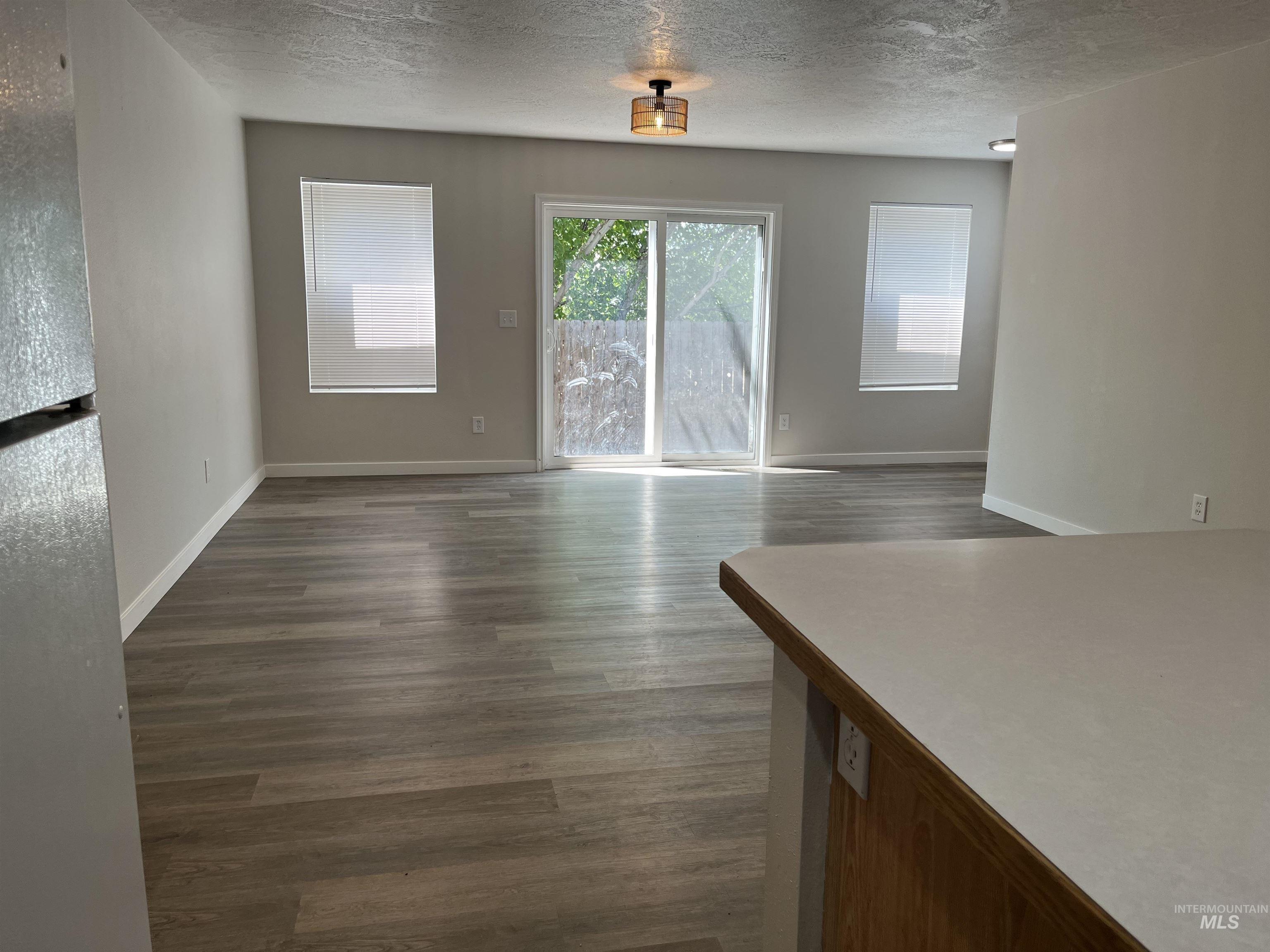 Unfurnished living area with dark wood-style flooring and a textured ceiling