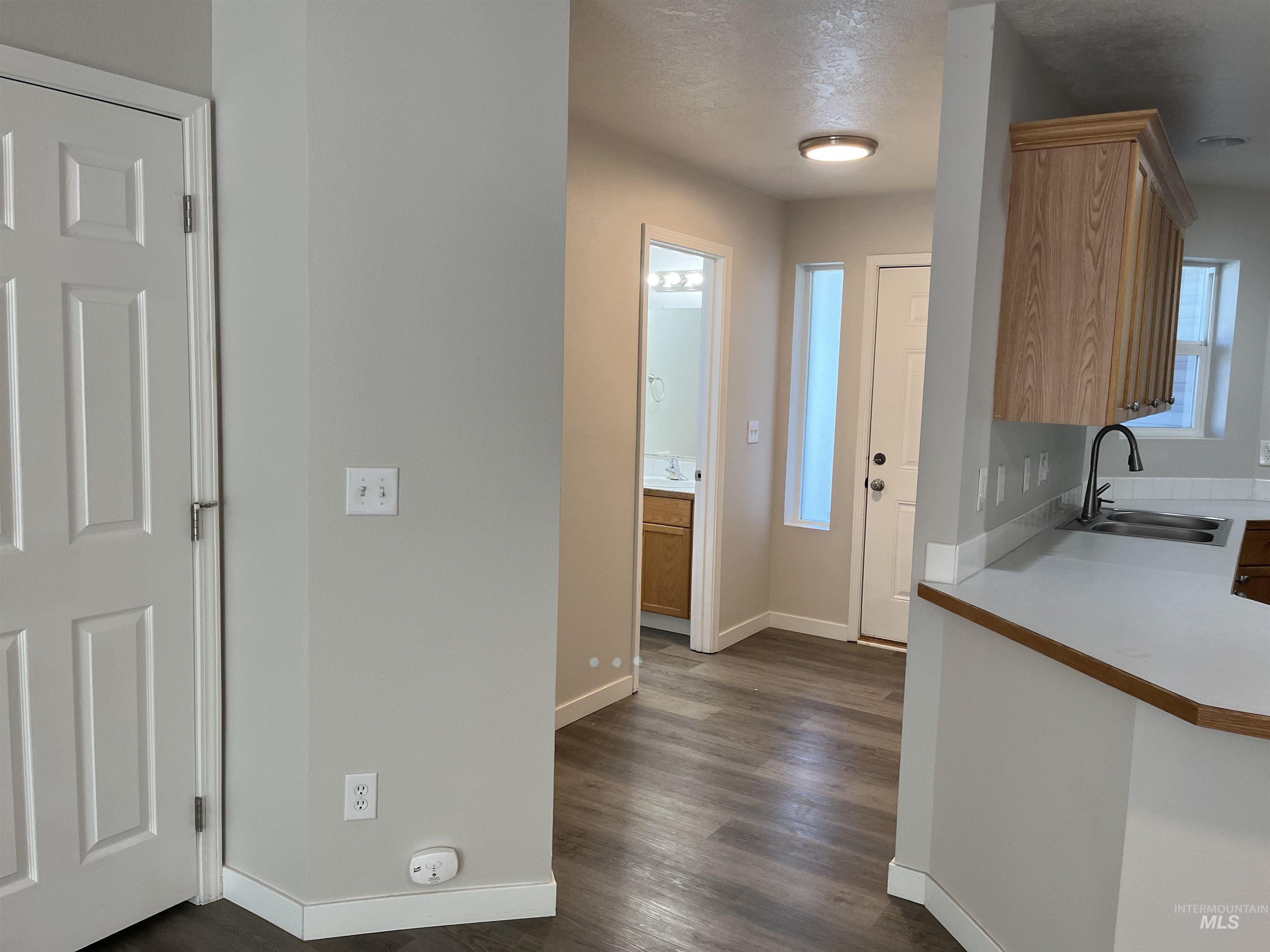 Kitchen featuring dark wood finished floors, light countertops, a textured ceiling, and brown cabinetry