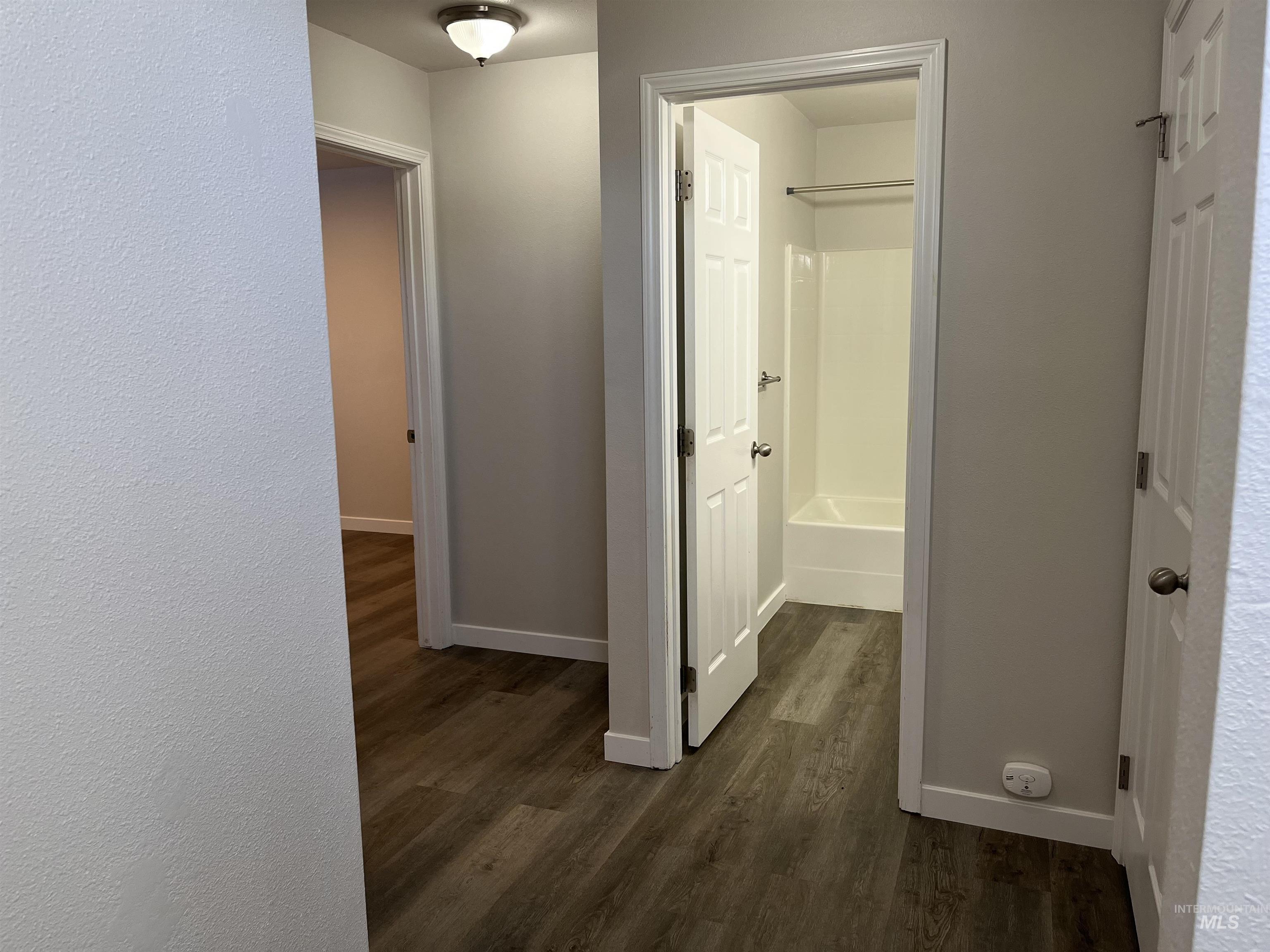 Hall with dark wood-type flooring and baseboards
