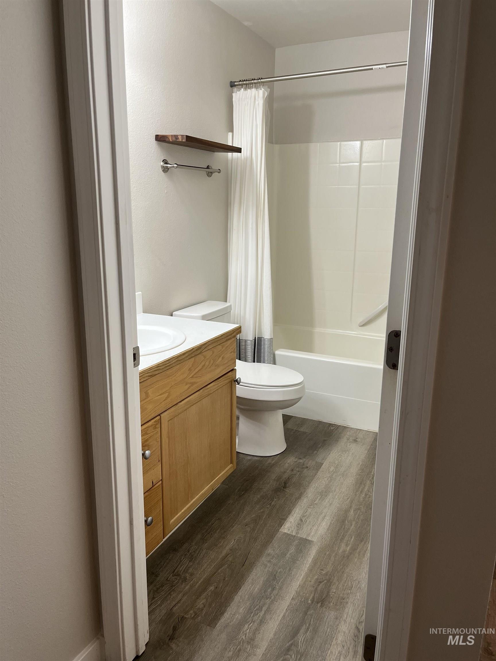 Full bathroom featuring wood finished floors, vanity, and shower / tub combo with curtain