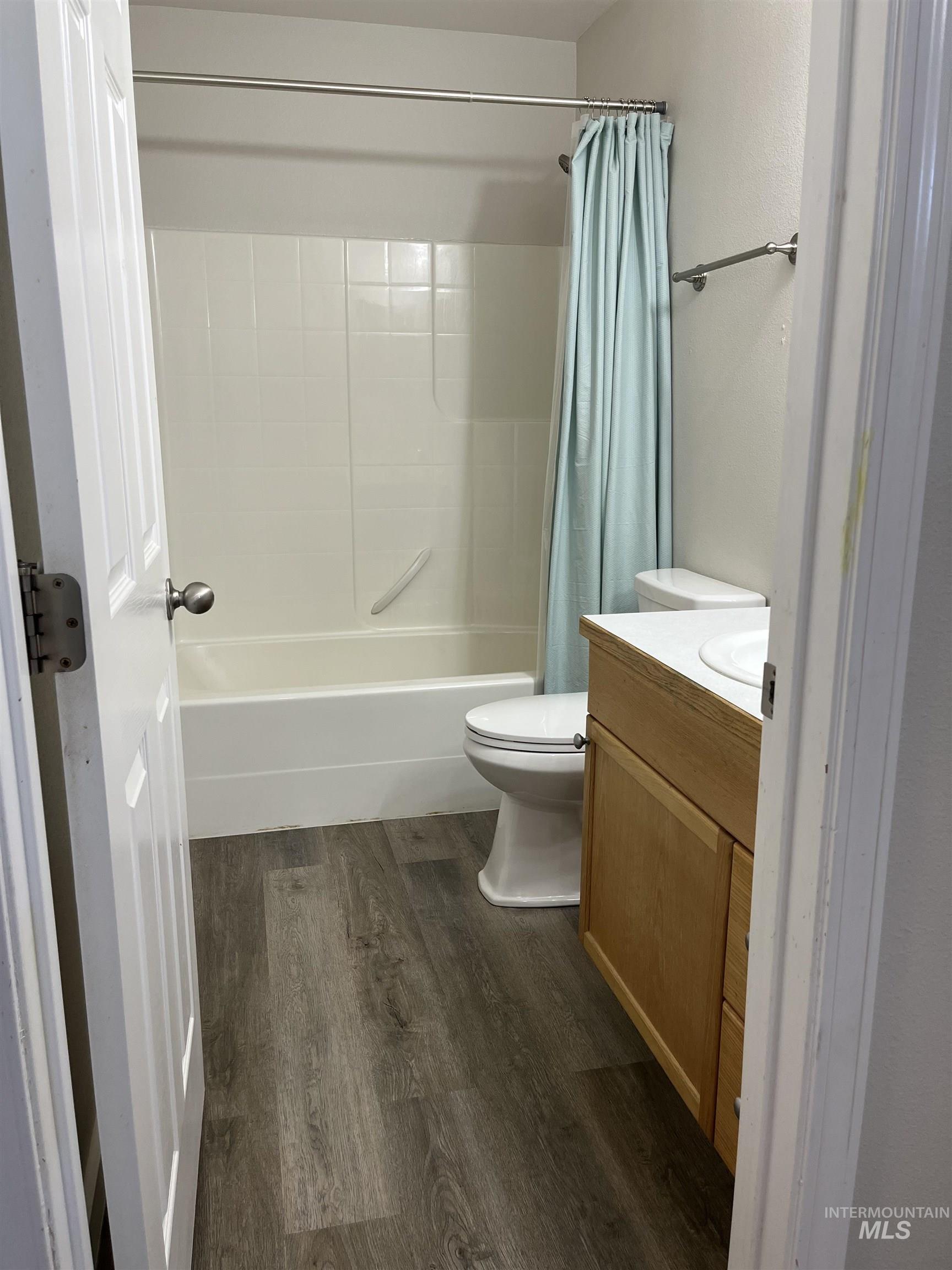 Bathroom with shower / tub combo with curtain, vanity, and wood finished floors