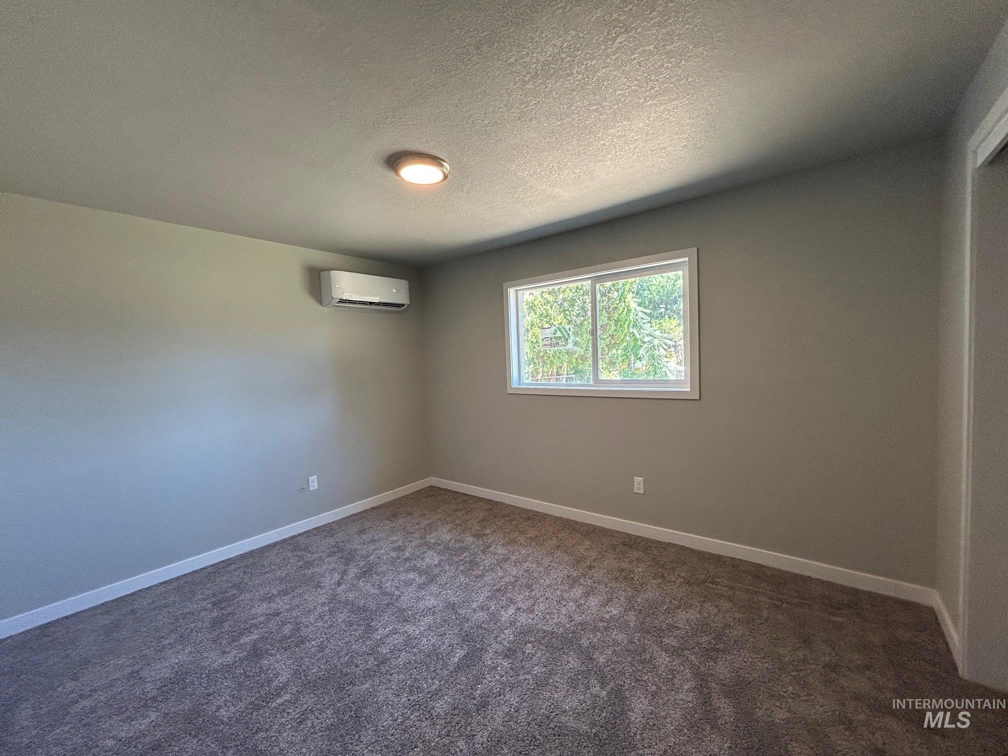 Empty room featuring dark carpet and a textured ceiling