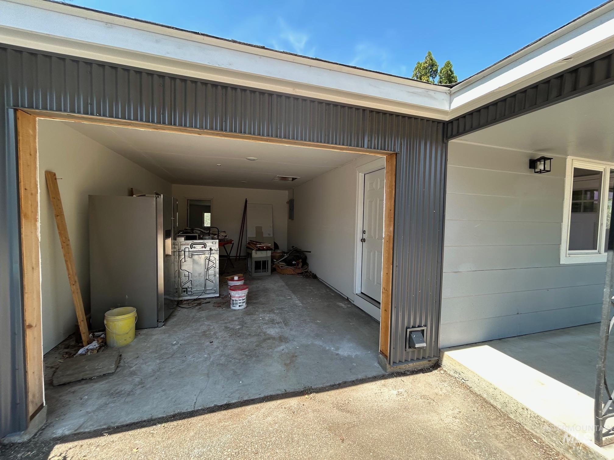 Garage featuring freestanding refrigerator and concrete driveway