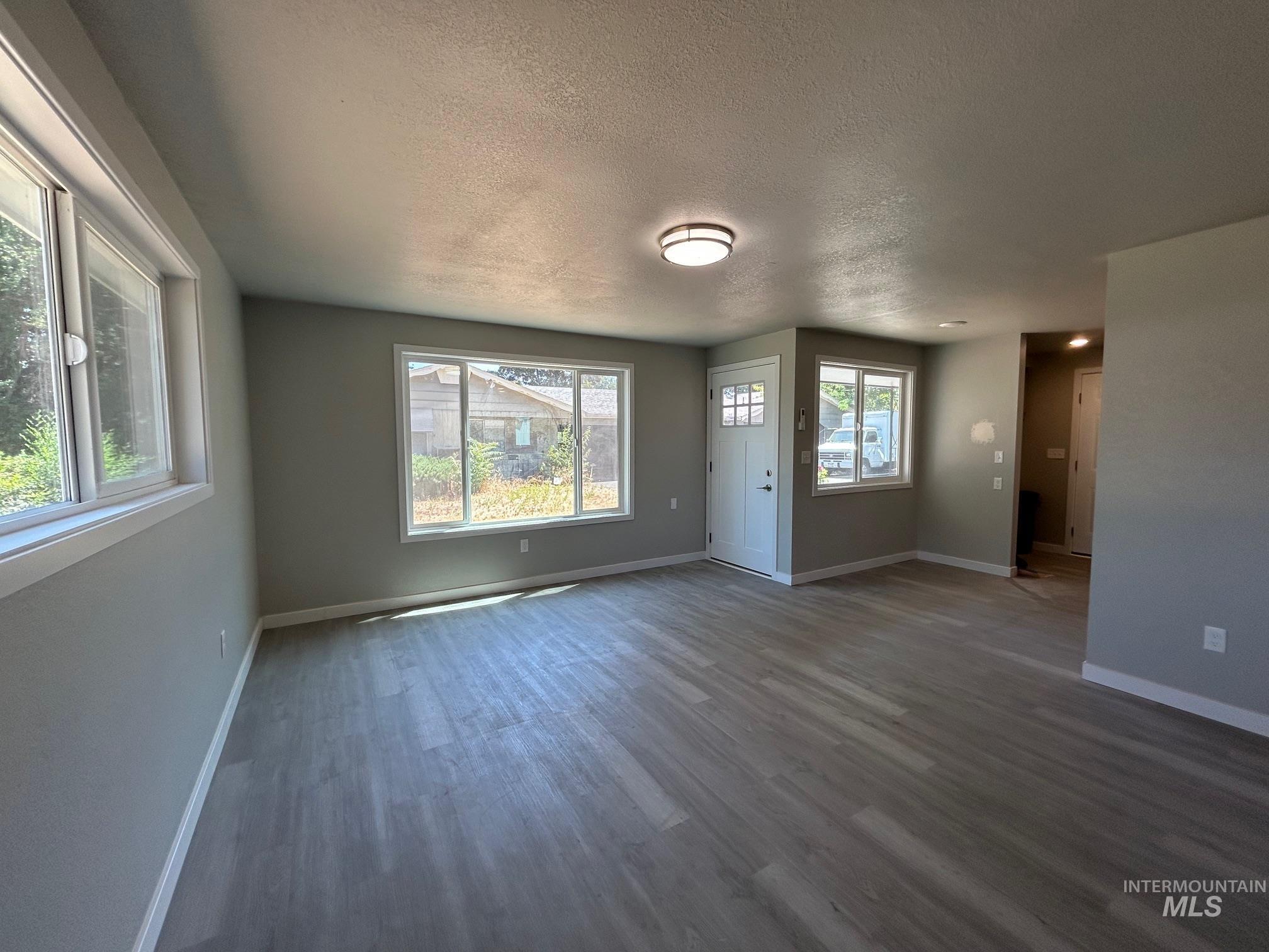 Unfurnished living room featuring a textured ceiling and wood finished floors