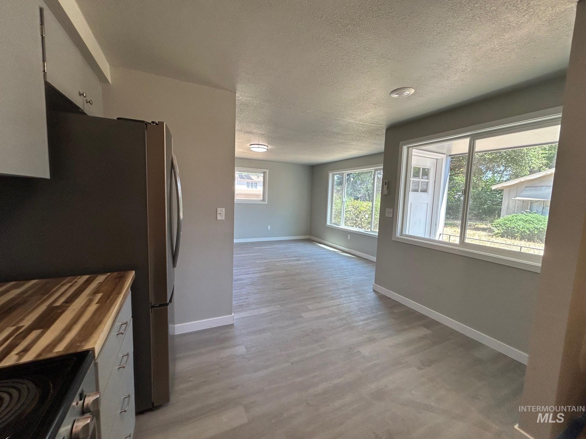 Kitchen with a textured ceiling, appliances with stainless steel finishes, and light wood-style flooring
